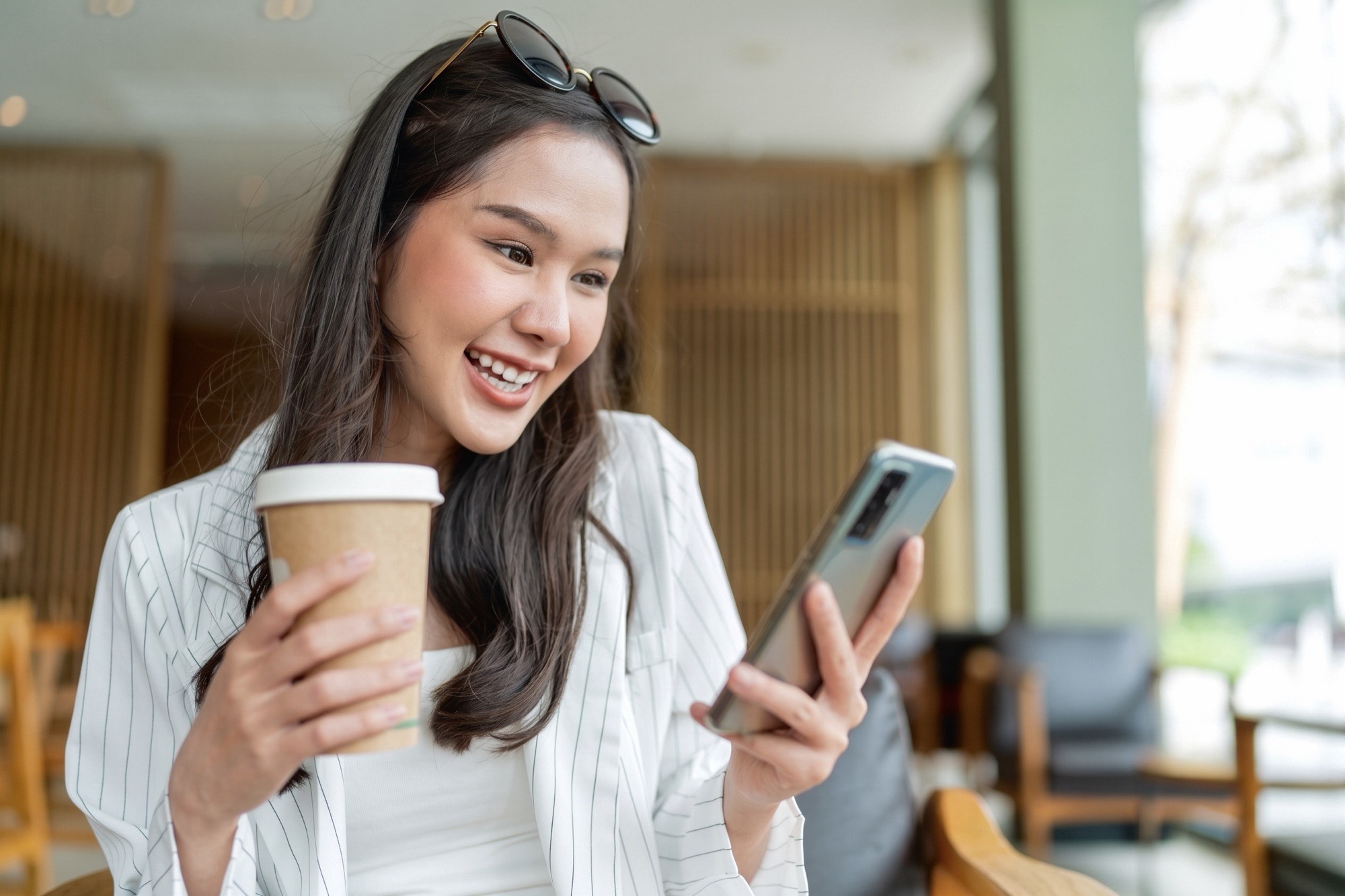 Aina smiling at her phone, coffee in hand